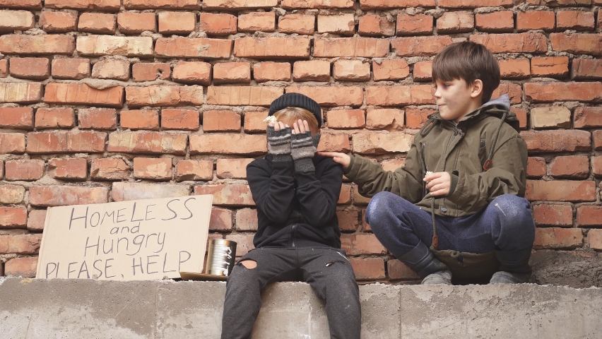Homeless kids beggars on the street with social message on the cardboard, suffer from poverty and loneliness.