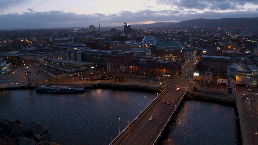 Belfast, Northern Ireland. City centre aerial flyover at dusk and during the night. River Lagan, City Hall, Victoria Square, Lagan Weir