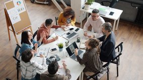 Office workers creative team are talking then doing high-five hand gesture working together around table. People and brainstorming activities concept. - Powered by Shutterstock - Get 15% off with code: PIKWIZARD15