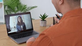 View over shoulder to a laptop screen with female tutor or colleague. Male freelancer or student communicates by video call, video meeting, online lesson