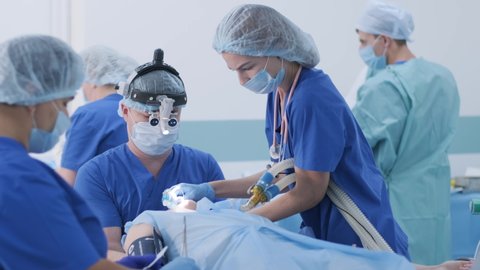 The anesthesiologist and medical team prepares female patient for surgery, puts patient into anesthesia, regulates oxygen mask, endotracheal tube. Surgery. Anesthesia