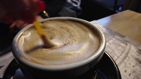Mixing sugar in cappuccino caffe, closeup shot