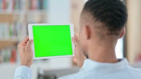 African Man Watching Tablet with Green Chroma Key Screen, Rear View
