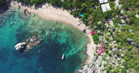 Top down Thailand's village aerial: mountains with jungle greenery, sandy beach on ocean shore, small lodges at palms. Epic Thai cityscape with of Koh Tao island, Tanote Bay. Paradise shot in 4K, UHD