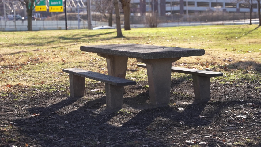 Handheld Slow Motion of Public Park Bench Under Sun in Fall Autumn Leaves and Sunny Weather and Grass