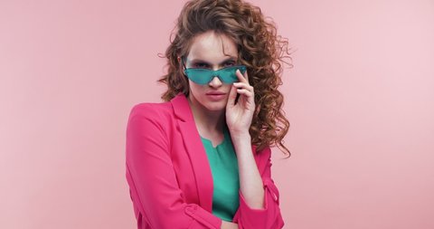 Glamorous Young female Model working at Studio, posing and looking Stylish. Pretty Woman Wearing Colorful trendy clothes. Having fashionable outfit. Looking stylish, touching her Eyeglasses.