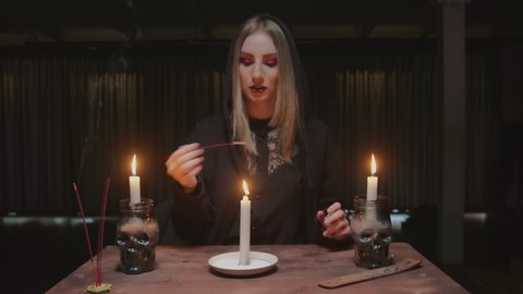 Young witch female fortune teller uses candle and incense stick in future telling ritual