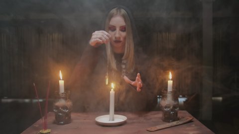 Young witch female fortune teller uses a blue magic crystal and candle in future telling ritual