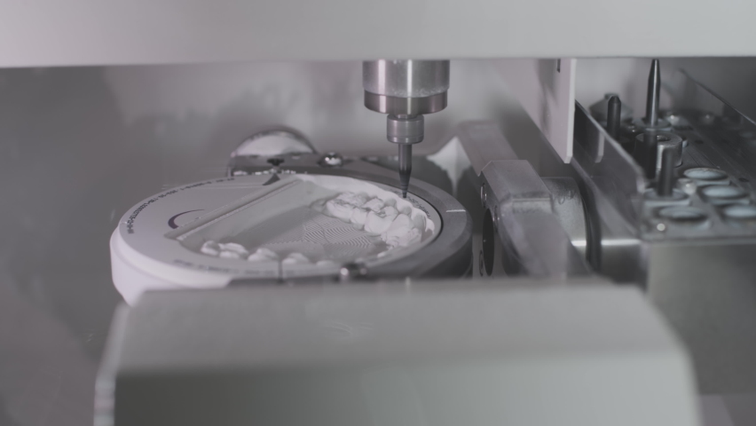 A professional CNC machine automatically creates a tooth prosthesis. The drill grinds an imitation of a ceramic jaw. Advanced technology in dentistry. Dental implant production. Royalty-Free Stock Footage #1066056376