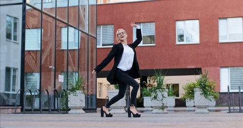 A  woman in office clothing dances on the business center territory. Active and fast business solutions.