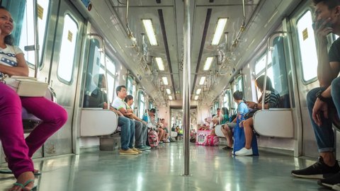 Manila, Philippines - May 27: Daytime timelapse view of people commuting on local train in Metro Manila, Philippines. Public transportation in Asia, daily commute and train travel concept.