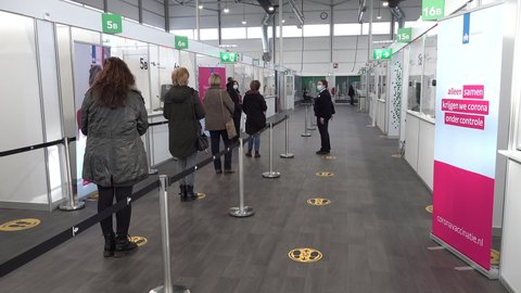 ROTTERDAM, NETHERLANDS – 21 JANUARY 2021: People stand in line waiting to be vaccinated in newly built event hall for Covid-19 coronavirus vaccinations at the Hague Rotterdam Airport