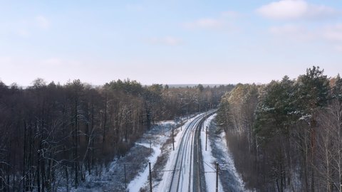 Electric train passing by railroad in the winter forest from aerial view.