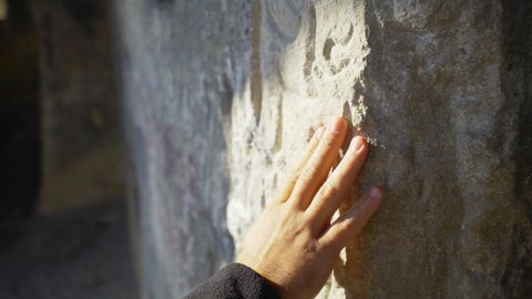 A man hand is touching Antique Rock tomb wall. Donalar rock tomb in Kastamonu