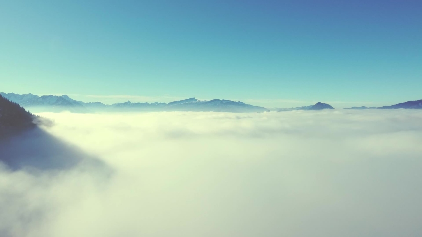 
An extraordinary mountain landscape above the fog. A drone flight that starts in the fog and rises above the fog


