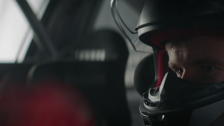 CU portrait of sports car driver closing helmet visor, starting a race on a speedway. Shot with 2x anamorphic lens Royalty-Free Stock Footage #1066088191