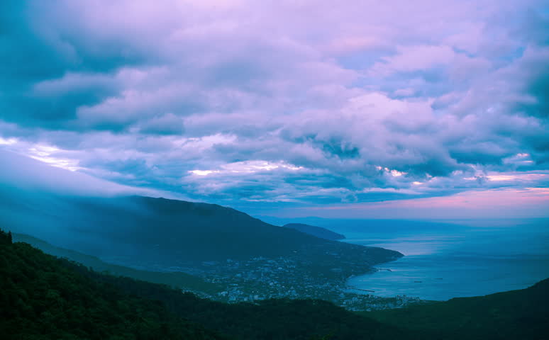dark stormy clouds above the mountains and the city in crimea. timelapse. 4k