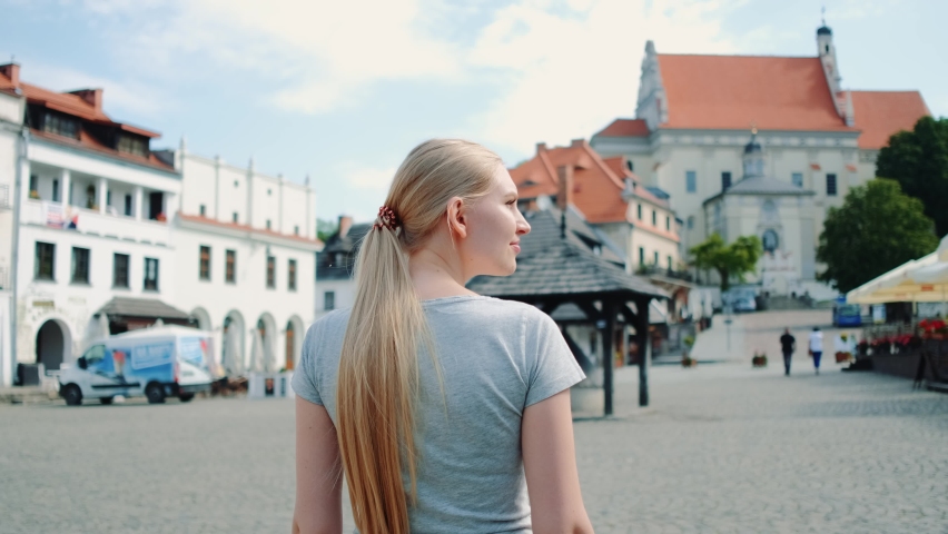 Back view of woman walking on the street in summer. She going sightseeing
