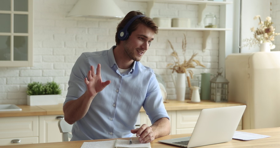 Happy young man in wireless headphones holding online video call meeting, giving educational lecture to students, studying remotely or negotiating working issues distantly with colleagues on computer. Royalty-Free Stock Footage #1066095910