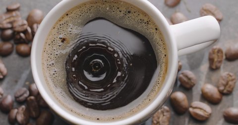 Drop of coffee slowly falls into a cup with coffee, top view, close-up, 300fps, Blackmagic Ursa Pro G2. 