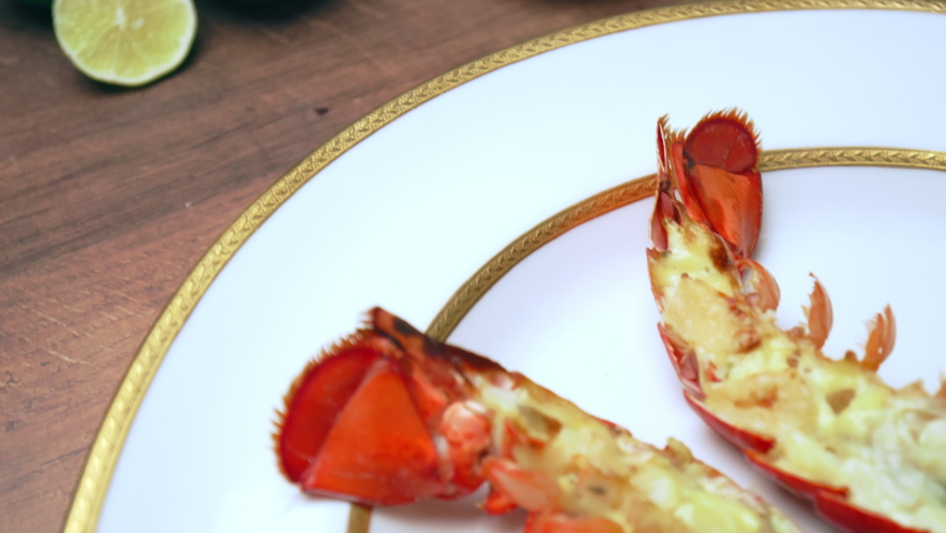 Close-up of grilled red lobster with sauces, butter and spices in serving plate. Concept of freshly made luxury seafood with tropical fruits and sauce on the side, a restaurant-style in 4K.
