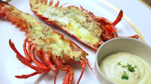 Close-up of grilled red lobster with sauces, butter and spices in serving plate. Concept of freshly made luxury seafood with tropical fruits and sauce on the side, a restaurant-style in 4K.