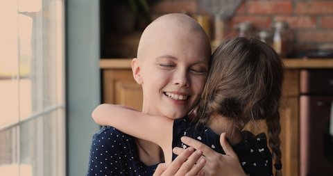 Close up young female bald cancer patient loving mom cuddling her little daughter feeling love receive support, kid rear back view, meaning of live, motivation for oncology disease struggle concept