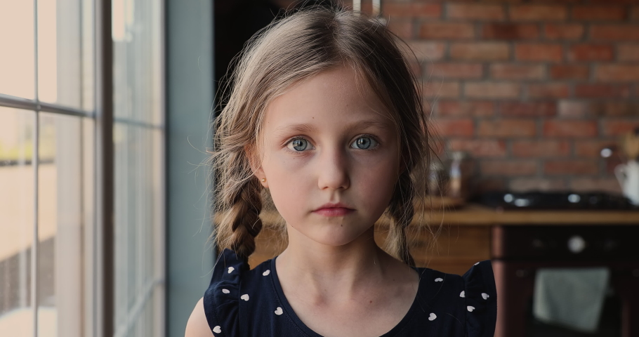 Head shot cute small 7s girl standing in kitchen smiles looks at camera. Adorable caucasian preschool child with pigtail poses indoors. Happy childhood, new Alpha generation offspring portrait concept Royalty-Free Stock Footage #1066121041