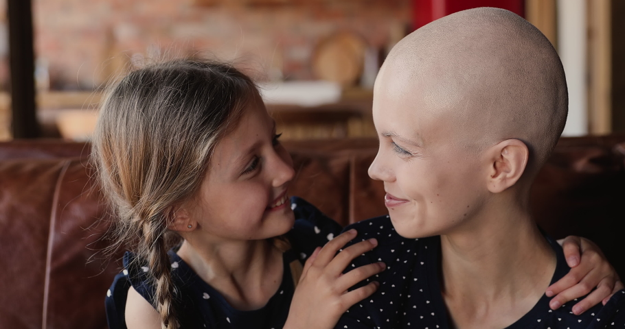 Close up little daughter hugs mother cancer patient. Happy family sit indoor embracing feeling grateful for remission, express love, kid girl supporting mom, encourage her, hoping in recovery concept Royalty-Free Stock Footage #1066121212