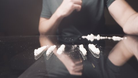 Cocaine junkie snorting line of coke or crushed pills with rolled US dollar bill. Drug Addiction. Illicit drug trafficking, illegal business. Habit, drug addiction. 4K. High quality 4k footage