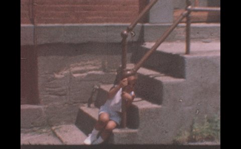 1960s: Child sits on steps.