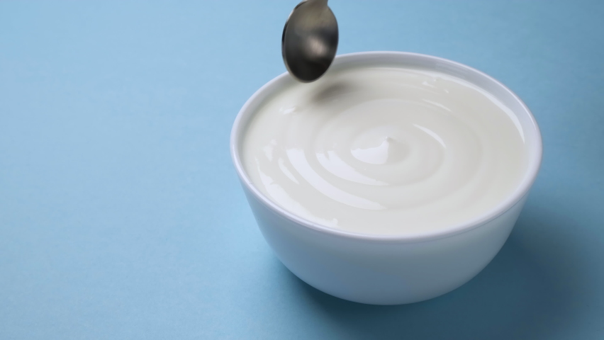 Bowl of fresh greek yogurt on blue background, sour cream with spoon Royalty-Free Stock Footage #1066128751