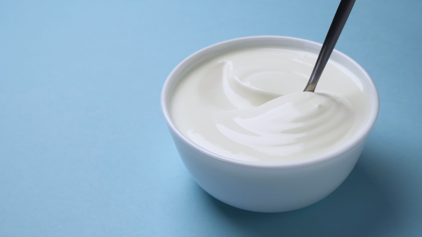Bowl of fresh greek yogurt on blue background, sour cream with spoon | Shutterstock HD Video #1066128751