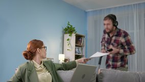 home office, pretty woman with glasses woman in jacket and pajama pants using modern technologies and applications on computer talks with customer via video link background of a man in headphones - Powered by Shutterstock - Get 15% off with code: PIKWIZARD15