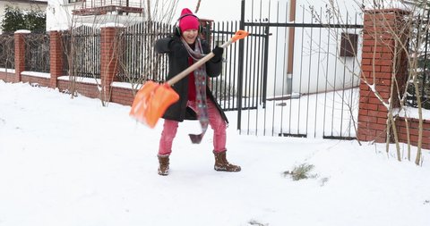 Woman cleans the road with a snow shovel, begins to play the shovel like a guitar. Funny woman in winter dancing with snow shovels and shovels snow