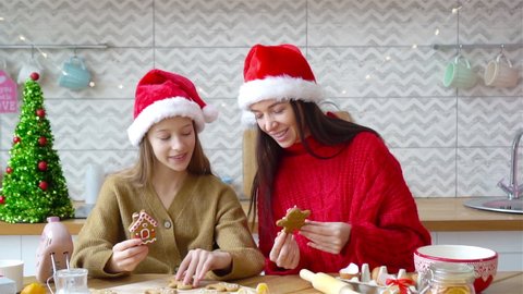 Family of mom and daughter in Santa Hat prepare Christmas cookies on the kitchen
