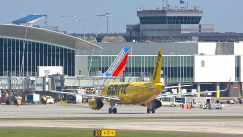 CHARLOTTE, NC - 2021: Spirit Airlines Airbus A320 Yellow Jet Airliner Taxiing and Arriving to Gate at Charlotte Douglas CLT International Airport with Ground Services outside Building Exteriors