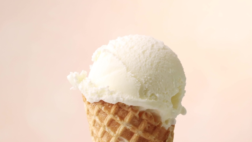melted caramel sauce flowing on vanilla ice cream scoop in waffle cone close up on beige background. perfect summer dessert Royalty-Free Stock Footage #1066144870