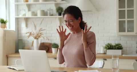 Overjoyed young caucasian woman in eyeglasses looking at laptop screen, celebrating getting email with good news, receiving dream job offer or excellent professional test results online at home.