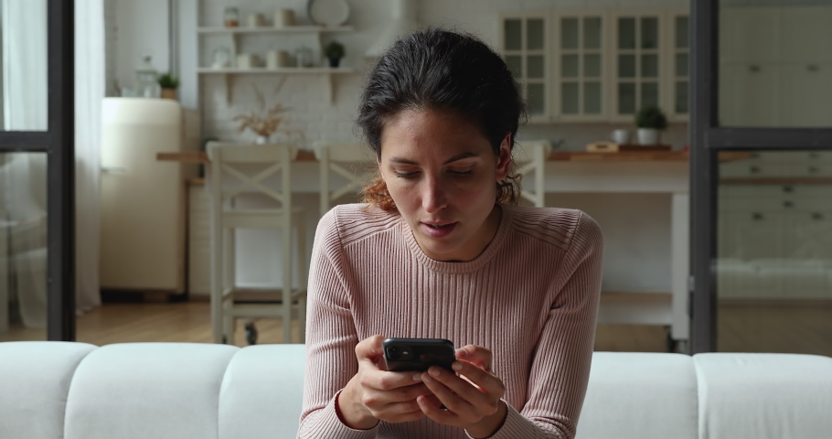 Confused young woman looking at mobile phone screen, feeling stressed of getting message with unpleasant scam news. Unhappy millennial caucasian lady dissatisfied with bad smartphone device work. Royalty-Free Stock Footage #1066150201