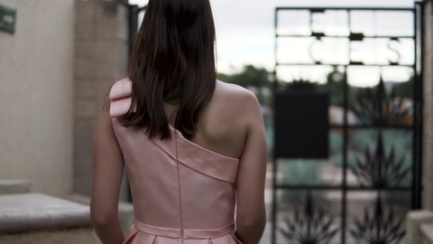 Backview of Brunette woman in pink dress passing through te gates of an Agave Plantation . Medium shot