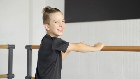 Young handsome boy dancer looking at the camera and smiling. Training at a ballet school.