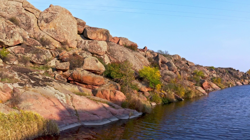Among the large boulders, a smooth shining stream flows in the evening warm light in picturesque Ukraine. Aerial UHD 4K drone realtime video, shot in 10bit HLG and colorized