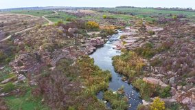 A small fast stream Kamenka in the wilderness in the evening light in Ukraine near which two people walk. Aerial UHD 4K drone realtime video, shot in 10bit HLG and colorized