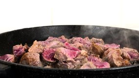 Pieces of beef meat being fried on hot pan,filmed in closeup in slow motion.Fresh red cow fillet frying for dinner at home kitchen
