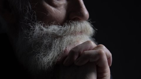 Aged male director with grey beard thinking about strategy on black background