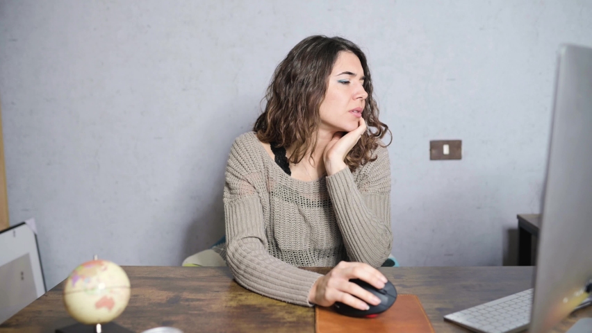 Young woman sitting at desk using computer surfing on internet.