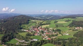 Slow descent footage of aerial photography with a drone in Bavarian forest near Grafenau overlooking the village of Grueb, Germany.