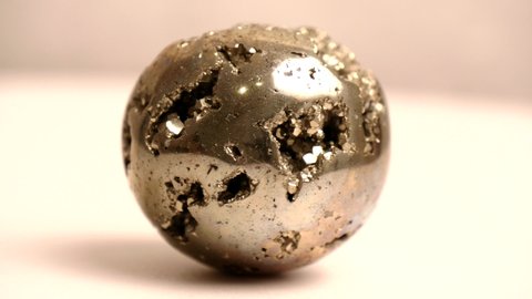 Pyrite ball. Beautiful ball of natural mineral Pyrite stands, lies on white background, spins in circle around its axis. Gems, minerals, collection of natural stones, close-ups, study of minerals.