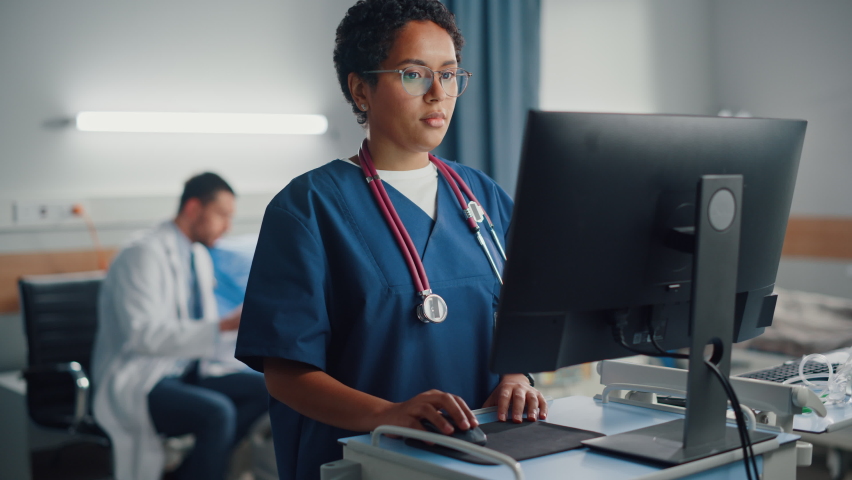 Hospital Ward: Professional Black Female Head Nurse Uses Medical Computer. In the Background Modern Equipment Clinic Doctor Consulting Patient Recovering After Successful Surgery in Bed | Shutterstock HD Video #1066174321